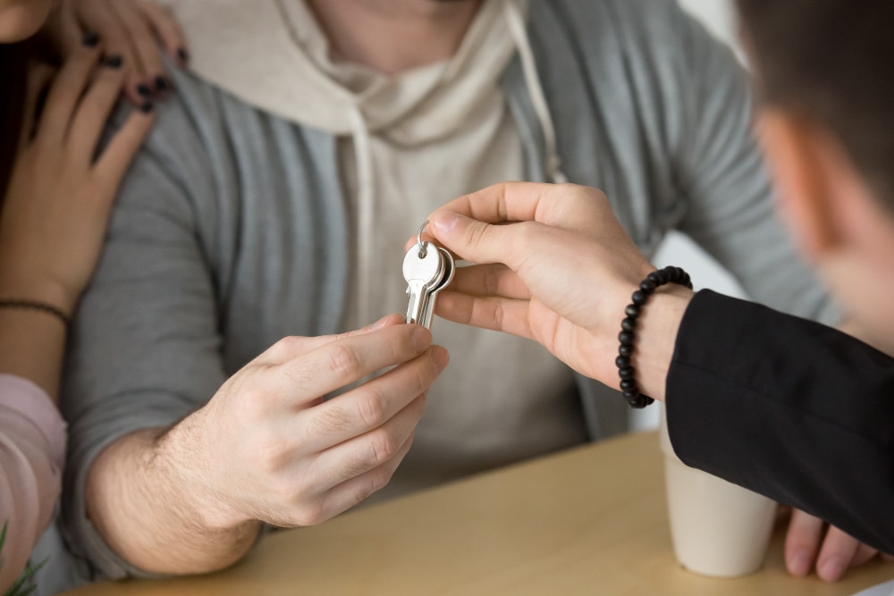 un propriétaire donnant les clés de son logement à ses nouveaux locataires